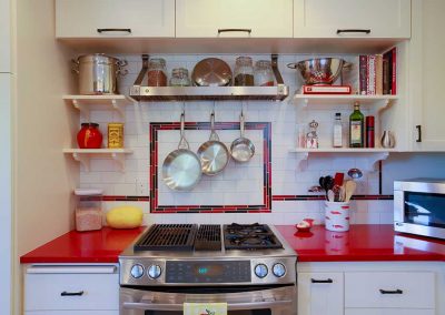 Retro Kitchen with Red Counter and Red and Black Tile Backsplash behind Stove
