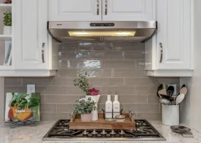 Countertop Stove with White Cabinets and Marble Countertop and Gray Tile Backsplash