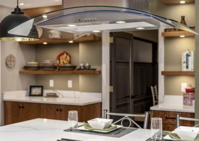 Modern Stove on Island Countertop with Overhead Vent and Bright Lighting